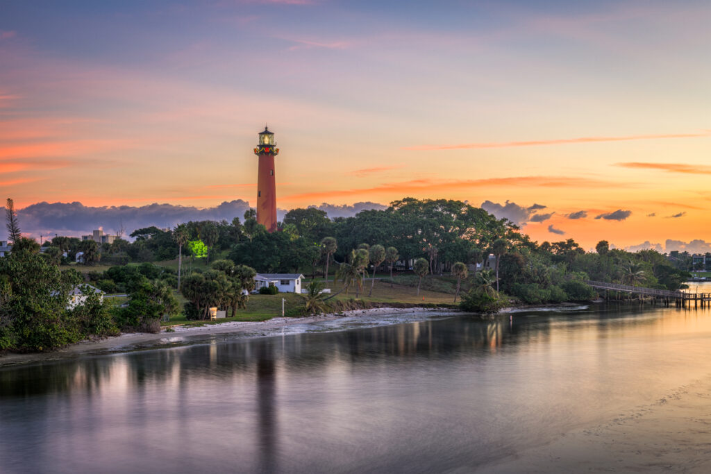 lighthouse near homes at sunset on the jupiter bay