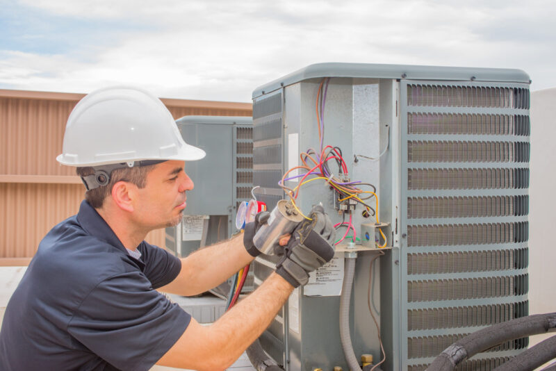 technician repairing ac unit installed on top of a business in jupiter, florida