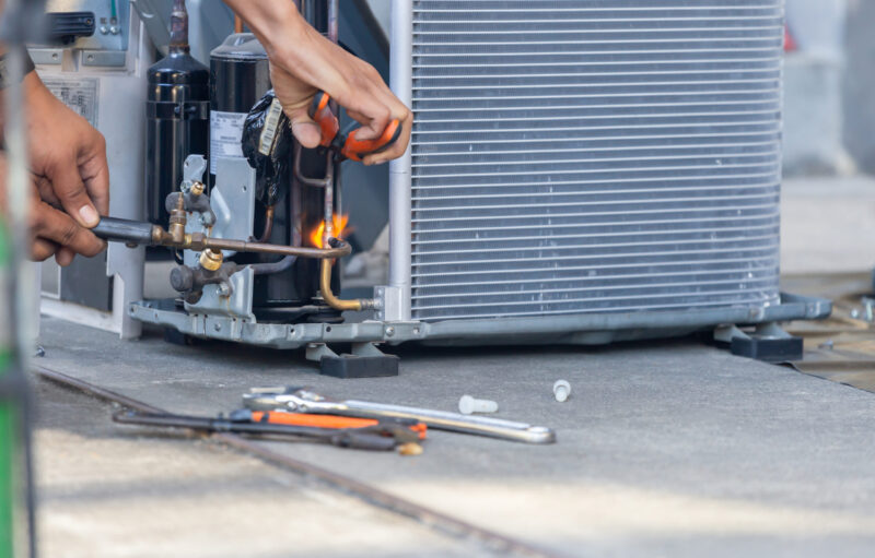 ac repair technician welding hoses on air conditioner outside a jupiter residence