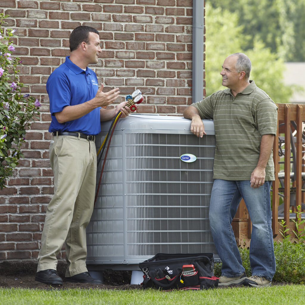 friendly technician talking to a homeowner standing beside their newly installed air conditioner