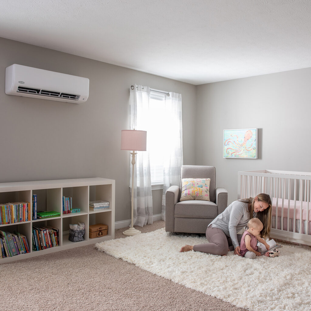 mother reading a book to her baby in the nursery that has a ductless unit installed on the wall