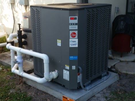 grey rheem heat pump installed to heat a pool outside a jupiter home