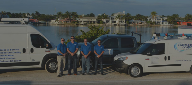 complete comfort air conditioning team standing outside next to company vehicles at the waterfront