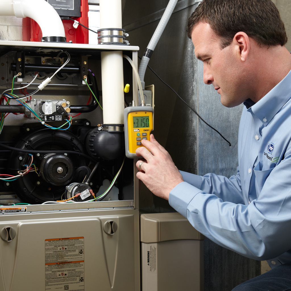 friendly technician running tests on a heating unit during a tune-up
